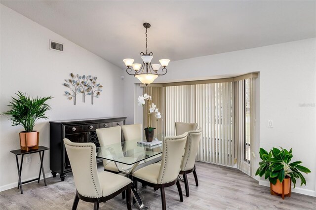 dining space with an inviting chandelier, vaulted ceiling, and hardwood / wood-style flooring