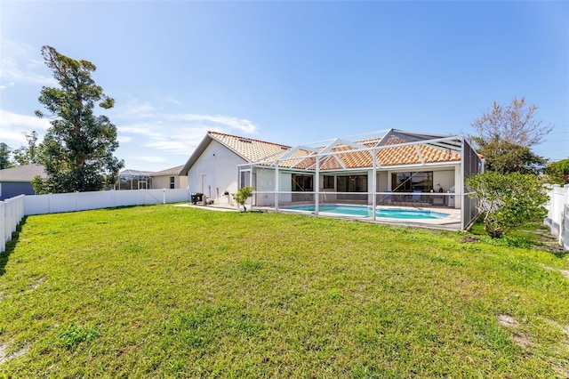 rear view of property with a lanai, a yard, and a fenced in pool