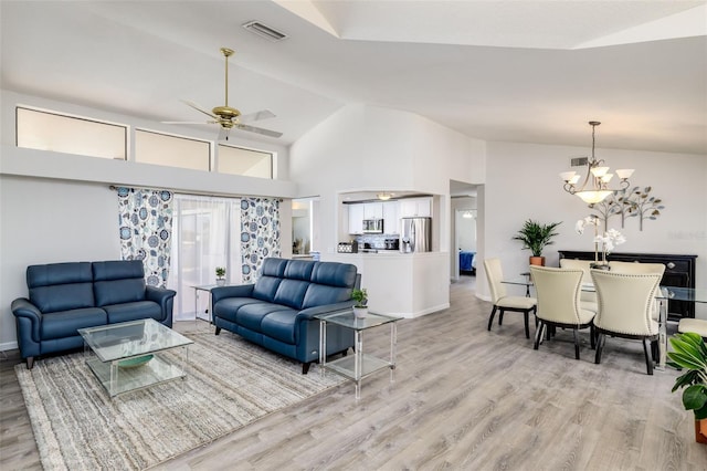 living room with ceiling fan with notable chandelier, light wood-type flooring, and lofted ceiling