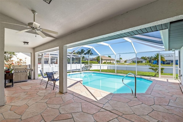 view of swimming pool featuring glass enclosure, ceiling fan, and a patio