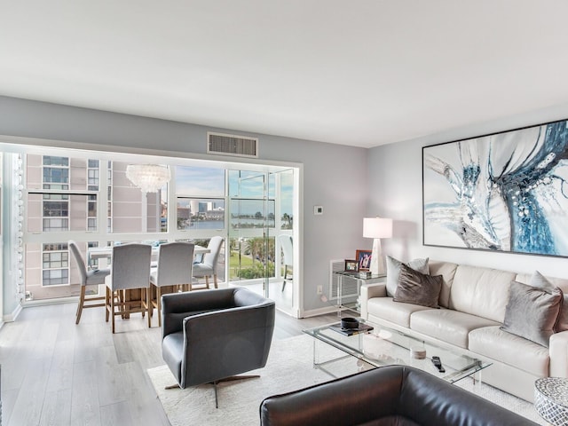 living room featuring heating unit, light hardwood / wood-style flooring, and a notable chandelier