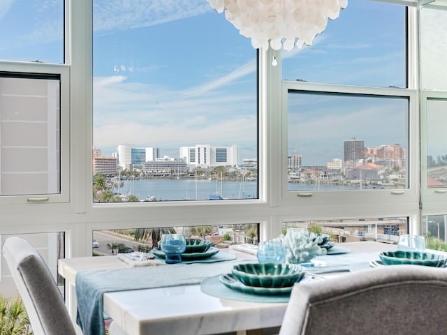 sunroom featuring plenty of natural light, a water view, and a chandelier