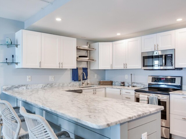 kitchen with stainless steel appliances, white cabinetry, a breakfast bar area, and sink