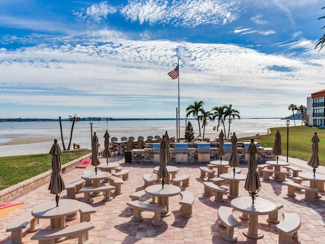 view of property's community featuring a water view, area for grilling, and a patio area