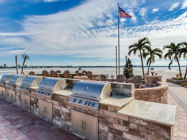 view of patio / terrace featuring grilling area, a water view, and exterior kitchen