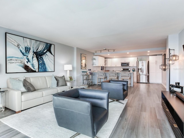 living room featuring track lighting, light hardwood / wood-style floors, and a chandelier