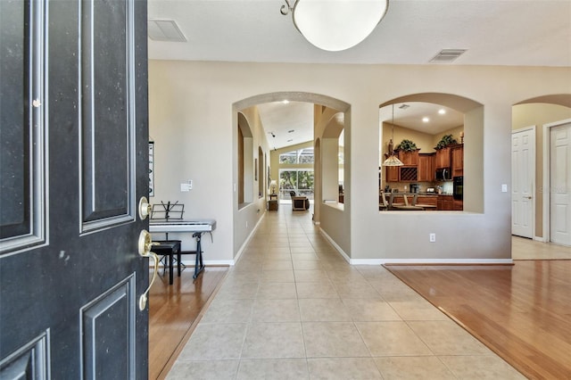 foyer with light tile patterned floors and vaulted ceiling