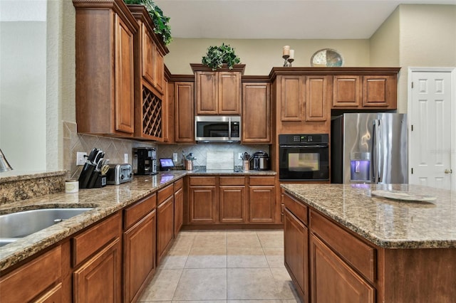 kitchen with light stone countertops, appliances with stainless steel finishes, and tasteful backsplash