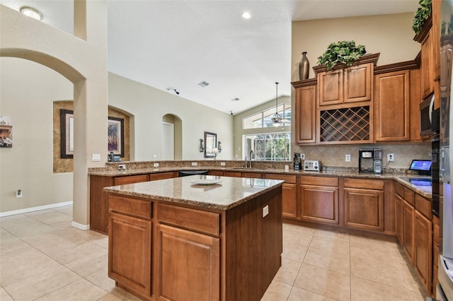 kitchen with sink, a kitchen island, tasteful backsplash, kitchen peninsula, and light tile patterned floors