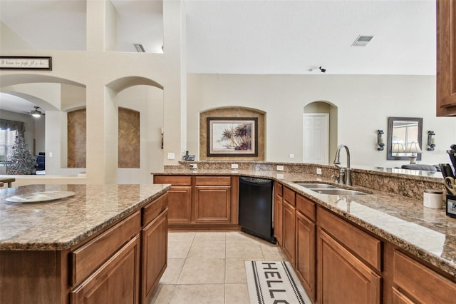 kitchen with sink, ceiling fan, black dishwasher, light tile patterned flooring, and light stone counters