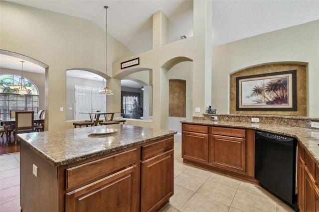 kitchen featuring an inviting chandelier, black dishwasher, decorative light fixtures, a kitchen island, and light stone counters