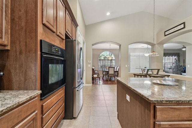 kitchen featuring light stone countertops, a center island, stainless steel refrigerator with ice dispenser, oven, and pendant lighting