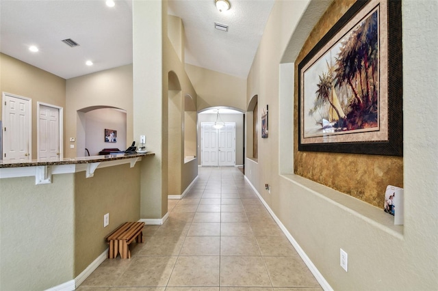 corridor featuring light tile patterned floors and a textured ceiling