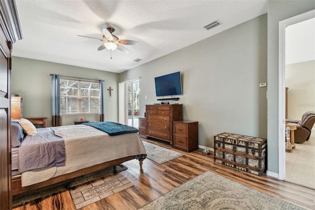 bedroom featuring ceiling fan, light hardwood / wood-style floors, and a textured ceiling