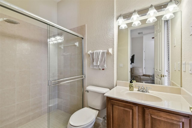 bathroom featuring vanity, a shower with shower door, and toilet