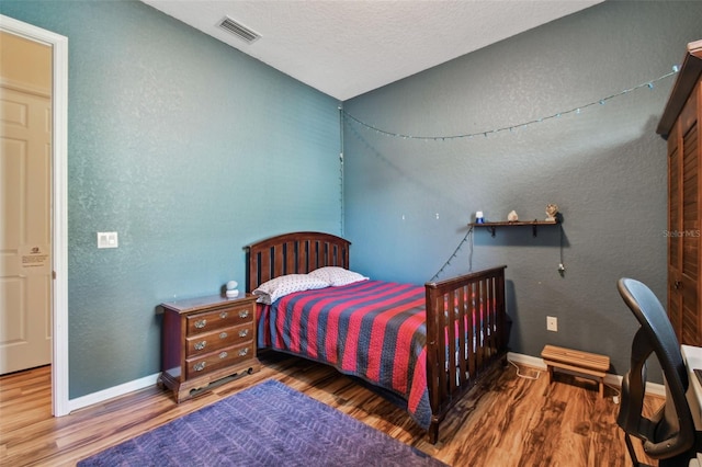 bedroom with hardwood / wood-style floors and a textured ceiling