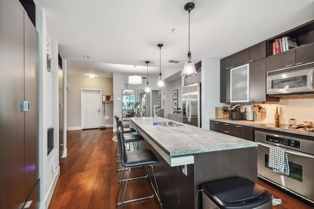 kitchen with pendant lighting, a breakfast bar, backsplash, sink, and stainless steel appliances