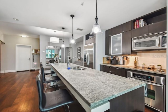 kitchen with decorative backsplash, sink, a center island with sink, and appliances with stainless steel finishes