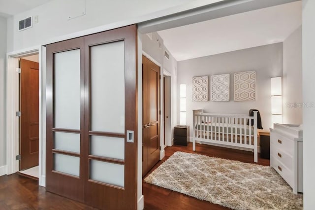 bedroom featuring a crib, a closet, and dark wood-type flooring