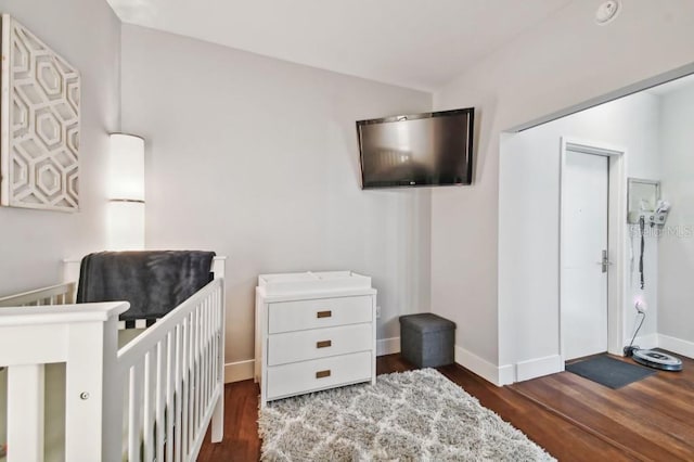 bedroom featuring dark hardwood / wood-style flooring and a nursery area