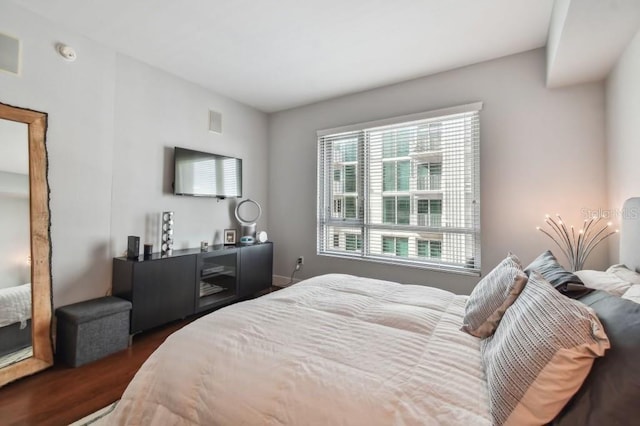 bedroom with dark hardwood / wood-style flooring and multiple windows