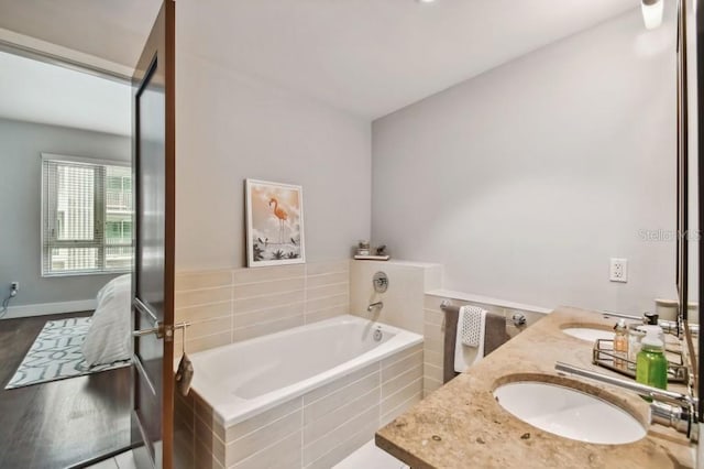 bathroom with vanity, a relaxing tiled tub, and hardwood / wood-style flooring