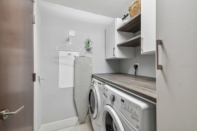 laundry area featuring cabinets, light tile patterned floors, and washing machine and clothes dryer