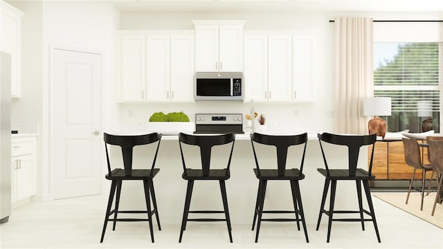 kitchen featuring white cabinets, stove, and a kitchen bar