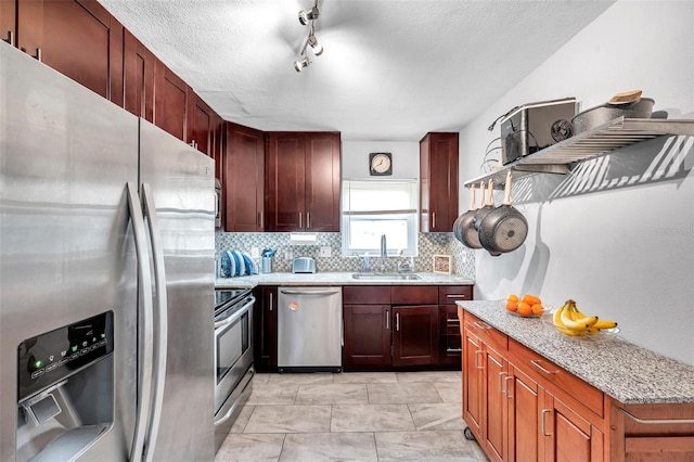 kitchen featuring a textured ceiling, appliances with stainless steel finishes, decorative backsplash, sink, and rail lighting