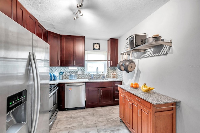 kitchen featuring tasteful backsplash, sink, appliances with stainless steel finishes, track lighting, and a textured ceiling