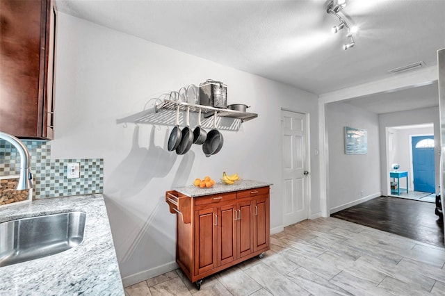 kitchen with tasteful backsplash, sink, light stone countertops, a textured ceiling, and rail lighting