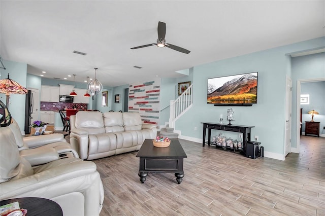 living room featuring ceiling fan with notable chandelier