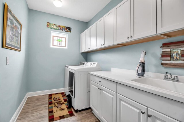 laundry area featuring cabinets, sink, hardwood / wood-style floors, and washing machine and clothes dryer