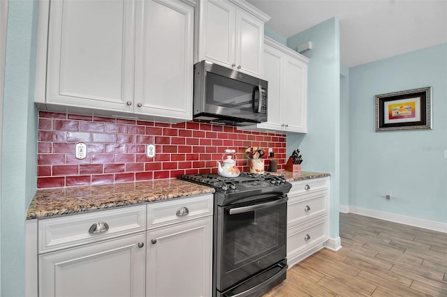 kitchen with white cabinetry, stone countertops, light wood-type flooring, gas range oven, and backsplash