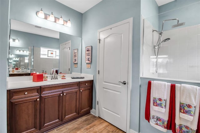 bathroom with tiled shower, vanity, and hardwood / wood-style floors