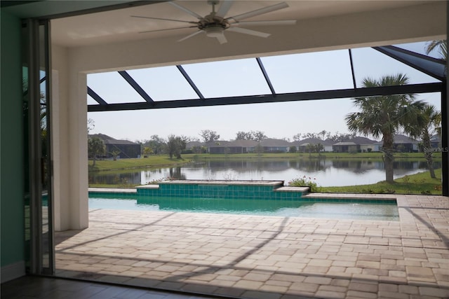 view of pool featuring ceiling fan, a patio area, glass enclosure, and a water view