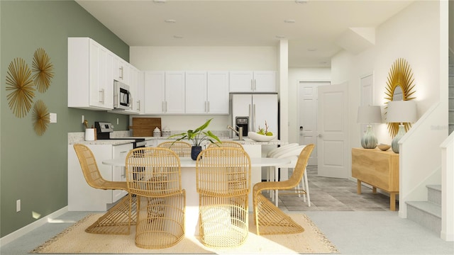 kitchen with sink, kitchen peninsula, a kitchen bar, white cabinets, and appliances with stainless steel finishes