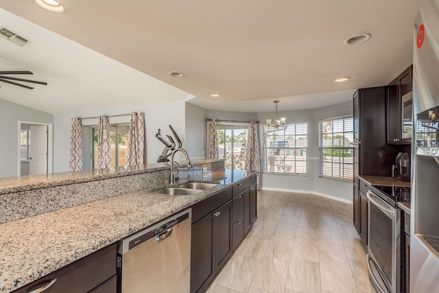 kitchen with dark brown cabinetry, light stone counters, sink, and stainless steel appliances