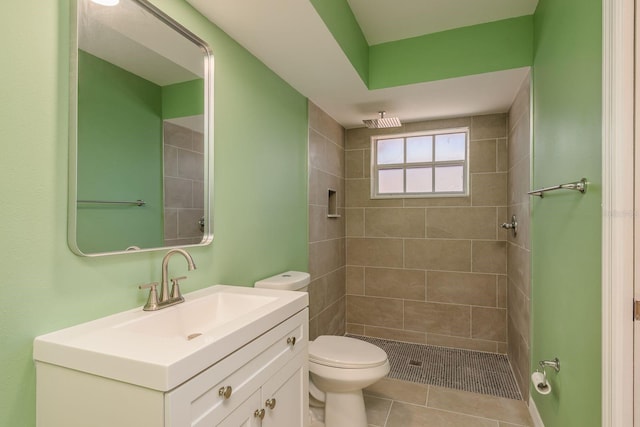 bathroom featuring tiled shower, tile patterned floors, vanity, and toilet