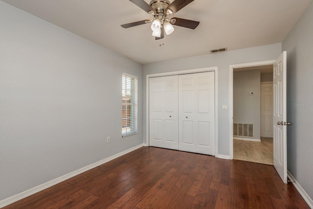 unfurnished bedroom featuring ceiling fan, a closet, and dark wood-type flooring