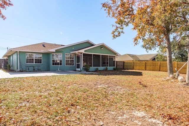 back of house featuring a lawn, a patio area, and a sunroom