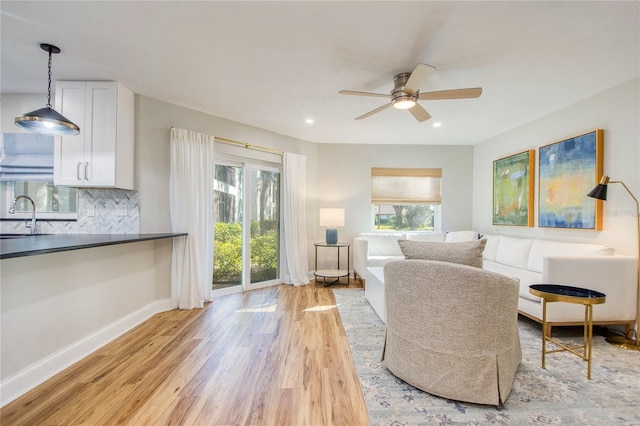 living room featuring light hardwood / wood-style flooring, ceiling fan, and sink