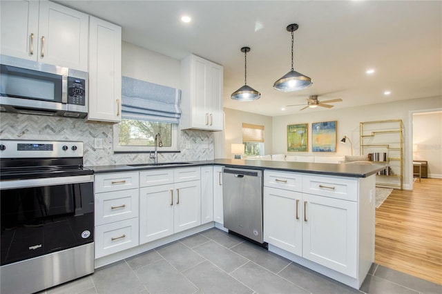 kitchen with white cabinets, sink, decorative light fixtures, kitchen peninsula, and stainless steel appliances