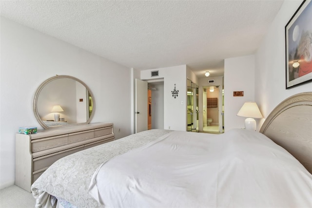 carpeted bedroom featuring ensuite bathroom and a textured ceiling