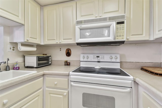 kitchen with white appliances, white cabinetry, and sink