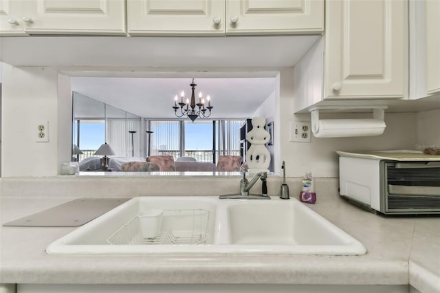 kitchen featuring white cabinetry, sink, decorative light fixtures, and an inviting chandelier