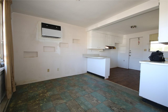 kitchen with beam ceiling, white cabinetry, and a wall unit AC