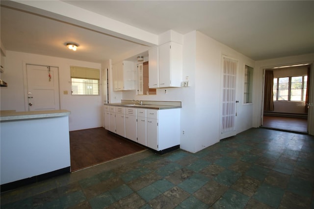 kitchen featuring white cabinets, a baseboard radiator, and sink