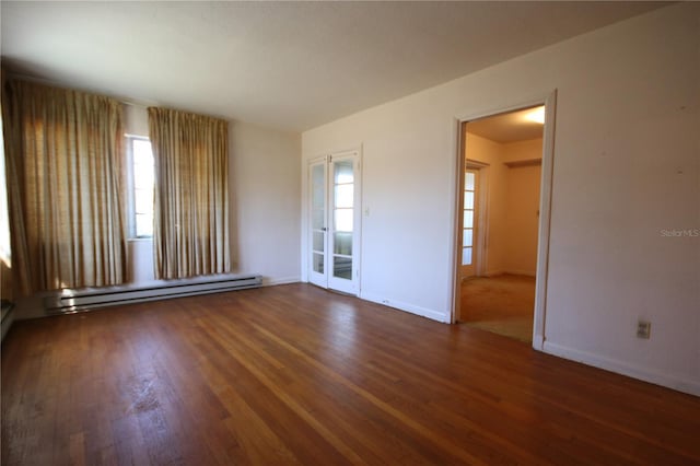 spare room with dark wood-type flooring and a baseboard heating unit