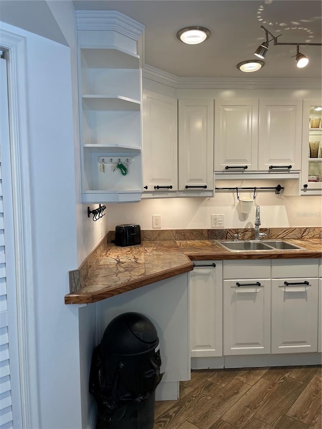 kitchen with white cabinets, dark hardwood / wood-style flooring, ornamental molding, and sink